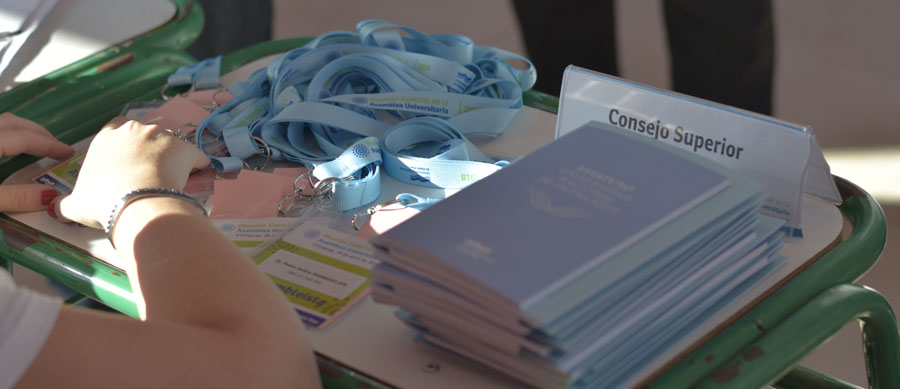 manos sobre una mesa con estatutos de uner y credenciales para asambleistas